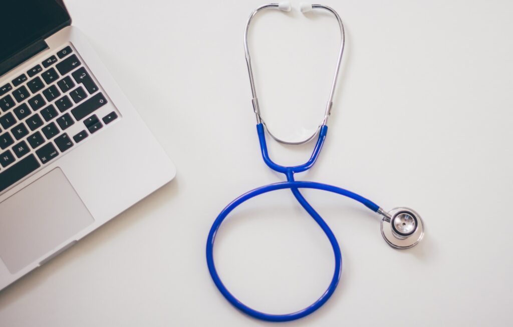 a blue stethoscope next to an open laptop